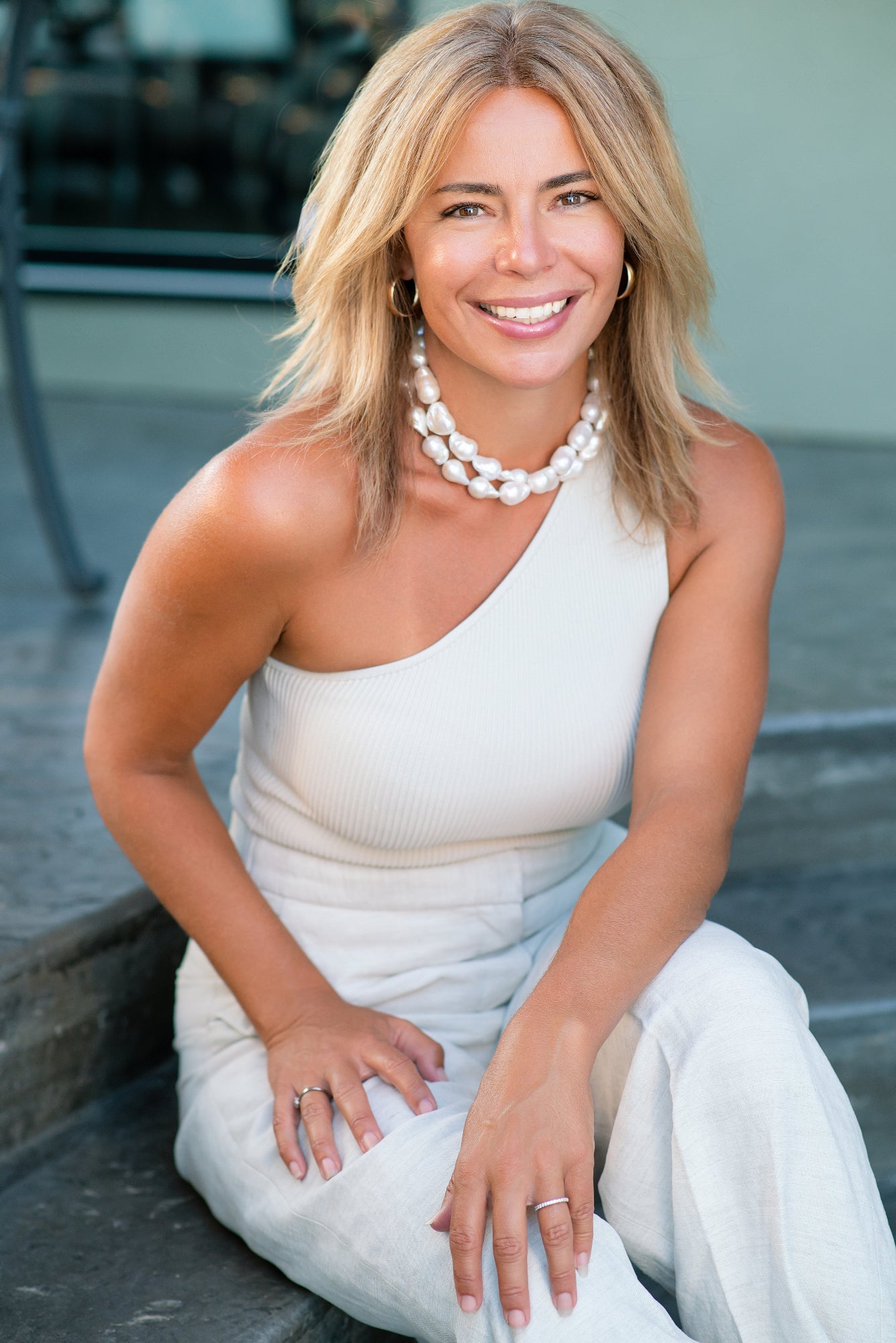Woman in a white dress sitting outdoors. Blanc Page Creative Agency Director Tarynn Liv Parker Introduces herself.