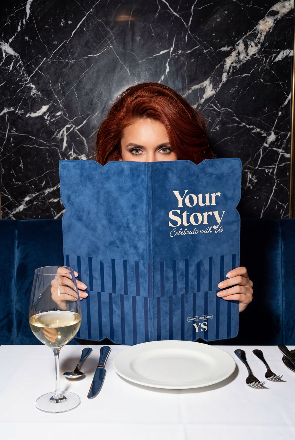 Woman holding a blue menu with 'Your Story' branding in a restaurant setting. Winery and Hospitality Branding that tells a story.
