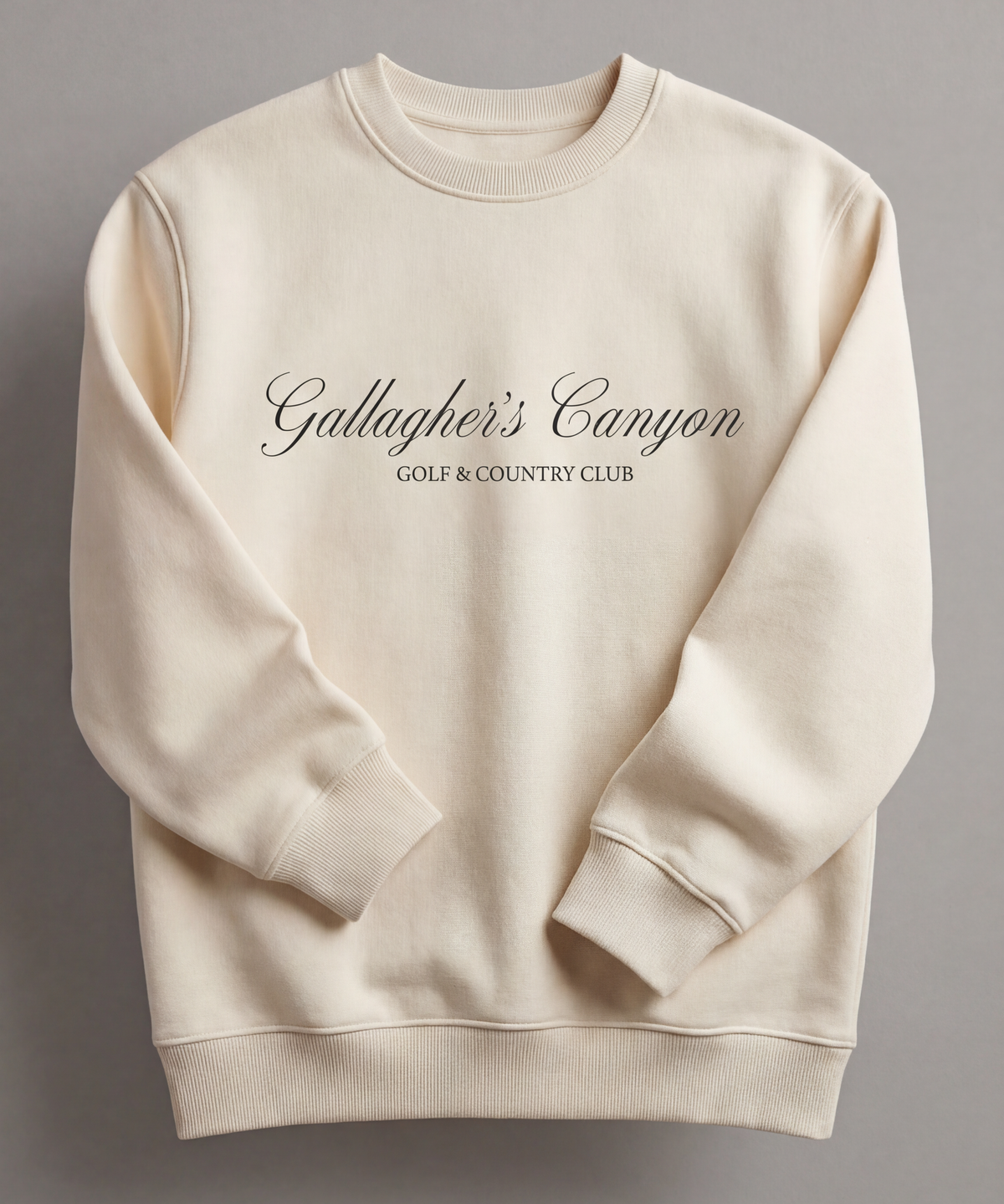A cream-colored sweatshirt with Gallaghers Canyon Golf  Country Club printed in elegant dark script on the front, displayed against a neutral background—perfect branded merchandise for wineries and hospitality venues.